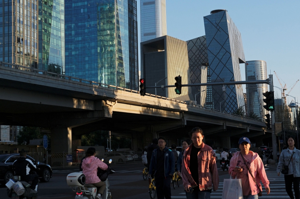 People cross an intersection near the central business district (CBD) in Beijing, China October 7, 2024. — Reuters pic