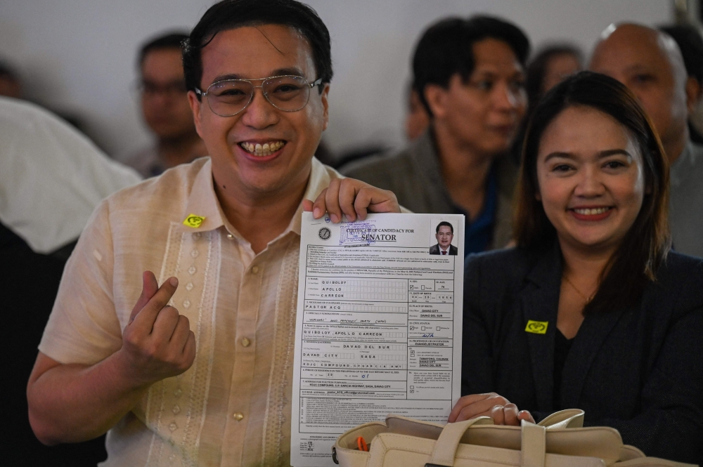 Lawyer Mark Christopher Tolentino (left) holds the application of Apollo Quiboloy, pastor and founder of the Philippine-based Kingdom of Jesus Christ (KOJC) church, as he files his candidacy for senator in the May 2025 midterm elections, in Manila on October 8, 2024. — AFP pic