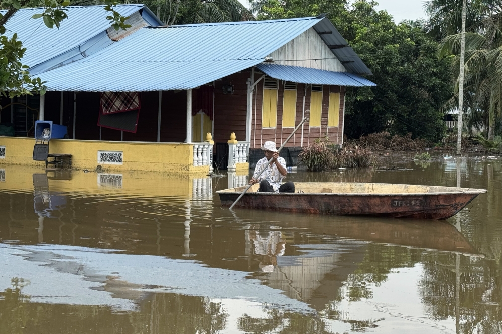 A resident of Kampung Sungai Linau in Simpang Renggam, Kluang, uses a boat to assess the condition of his home, which has been submerged in floodwaters since last Saturday. — Bernama pic 