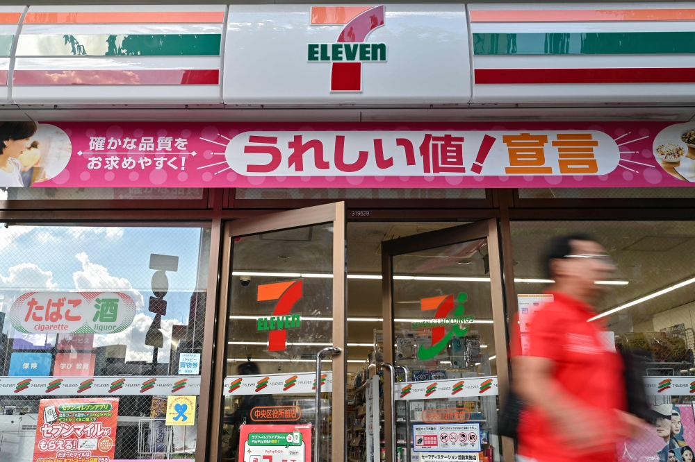 (FILES) A man walks out of a 7-Eleven convenience store along a street in central Tokyo on September 9, 2024. In Japan more is at stake than money in the mammoth takeover battle for 7-Eleven, the world's biggest convenience chain, – AFP pic