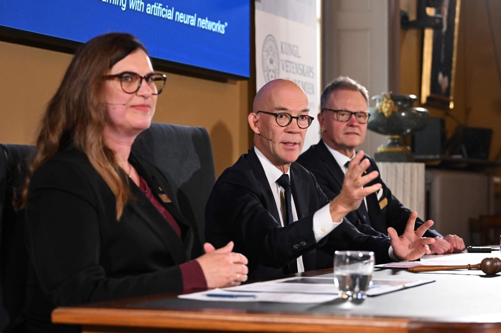 Secretary General of the Royal Swedish Academy of Sciences Hans Ellegren (centre) addresses media representatives next to Chair of the Nobel Committee for Physics Ellen Moons (left) and Member of the Nobel Committee for Physics Anders Irbaeck following their announcement of the 2024 Nobel Prize in Physics at the Royal Swedish Academy of Sciences in Stockholm, Sweden on October 8, 2024. — AFP pic