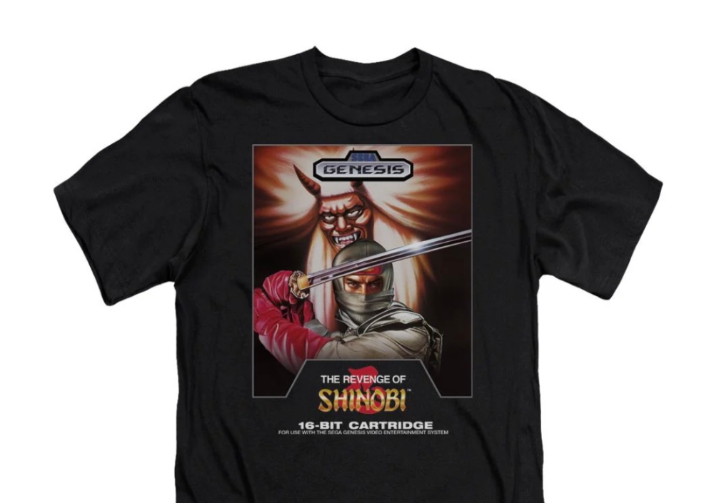 The picture shows a Shinobi t-shirt being sold on the official Sega storefront. Shinobi was originally created for Japanese arcades in 1987 and features a ninja character who fights to stop a criminal organisation that kidnaps child ninjas. — Picture via Sega Official store