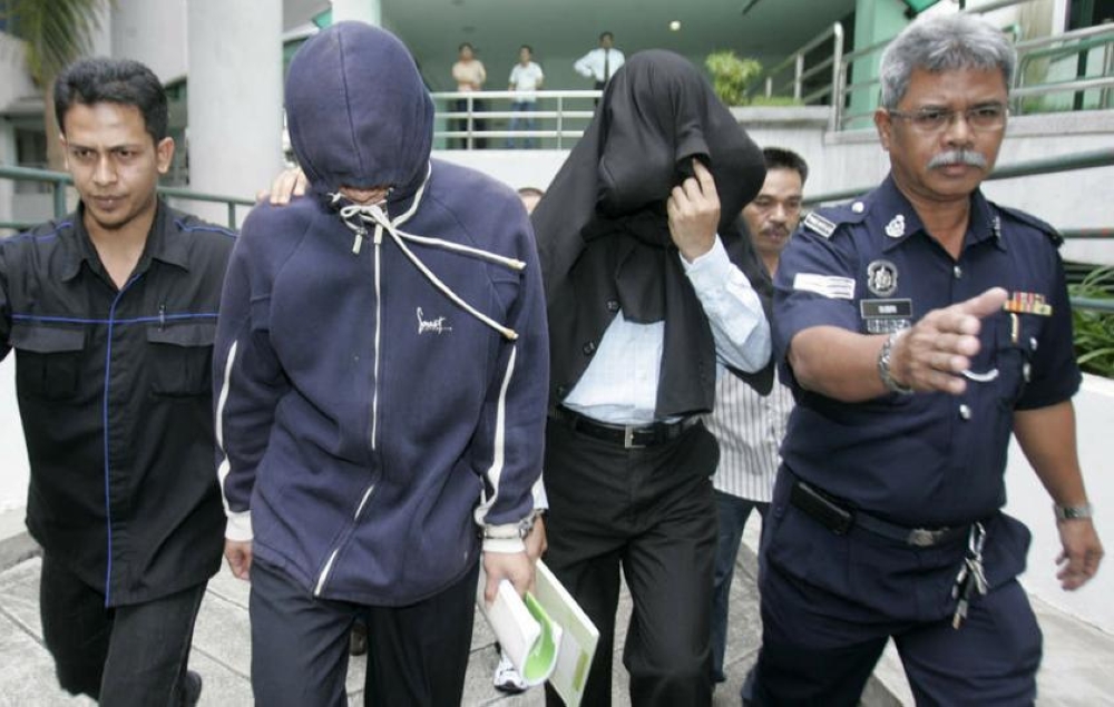 File photo of ex-policemen Azilah Hadri and Sirul Azhar Umar (heads covered). The Court of Appeal in Putrajaya on August 23, 2013 overturned their conviction of murdering Mongolian model Altantuya Shaariibuu. - Reuters pic