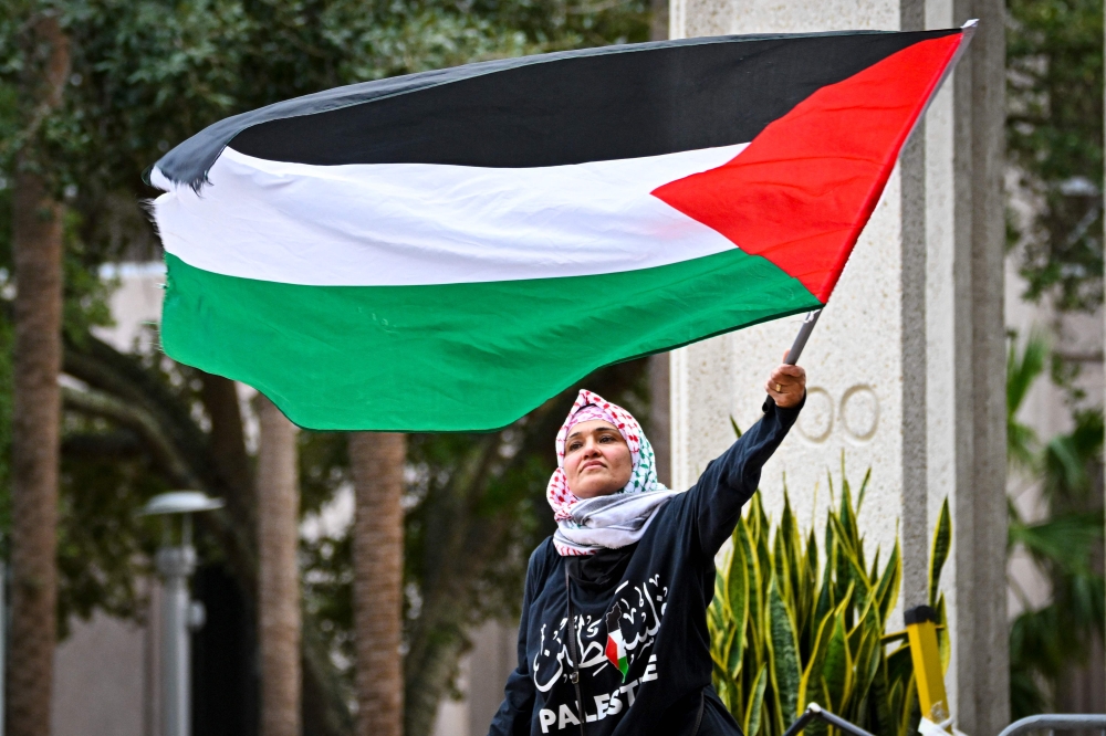 A pro-Palestinian protester waves a Palestine flag as people rally in support of Gaza and Lebanon in front of the City Hall to mark one year of the war between Hamas and Israel in Orlanda, Florida, on October 5, 2024. — AFP pic