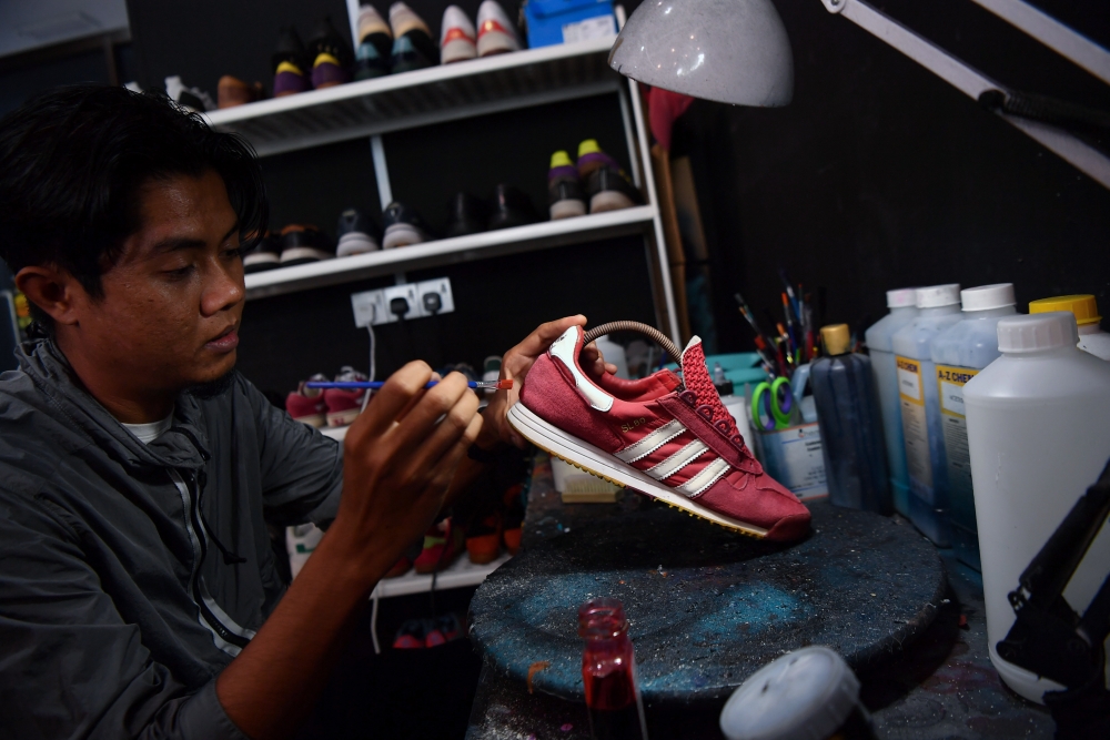 Firm Bundle employee, Nasrul Aman Azmi, 29, applies colour on shoes at Firm Bundle Boutique in Taiping. In addition to offering shoe spa services, the boutique also sells items such as shoes, shirts, track pants, shorts, bags and other accessories from various international brands such as Stone Island, Fred Perry, Cp Company, Lyle n Scott, Adidas, Preety Green, Weekend Offender and Napapijri. — Bernama pic