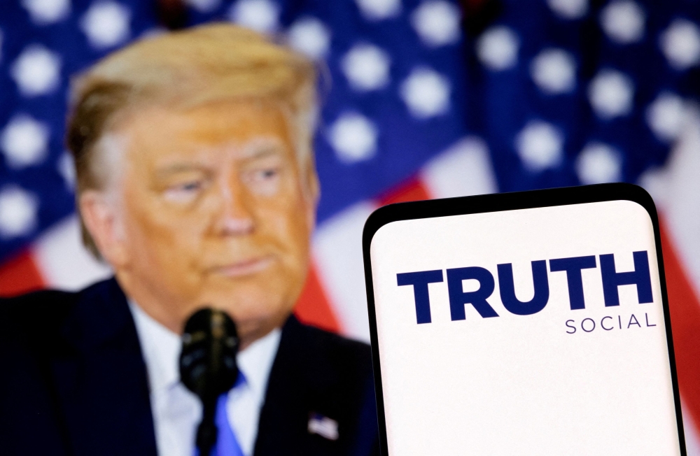 The Truth Social network logo is seen on a smartphone in front of a display of former US President Donald Trump in this picture illustration taken February 21, 2022. — Reuters pic