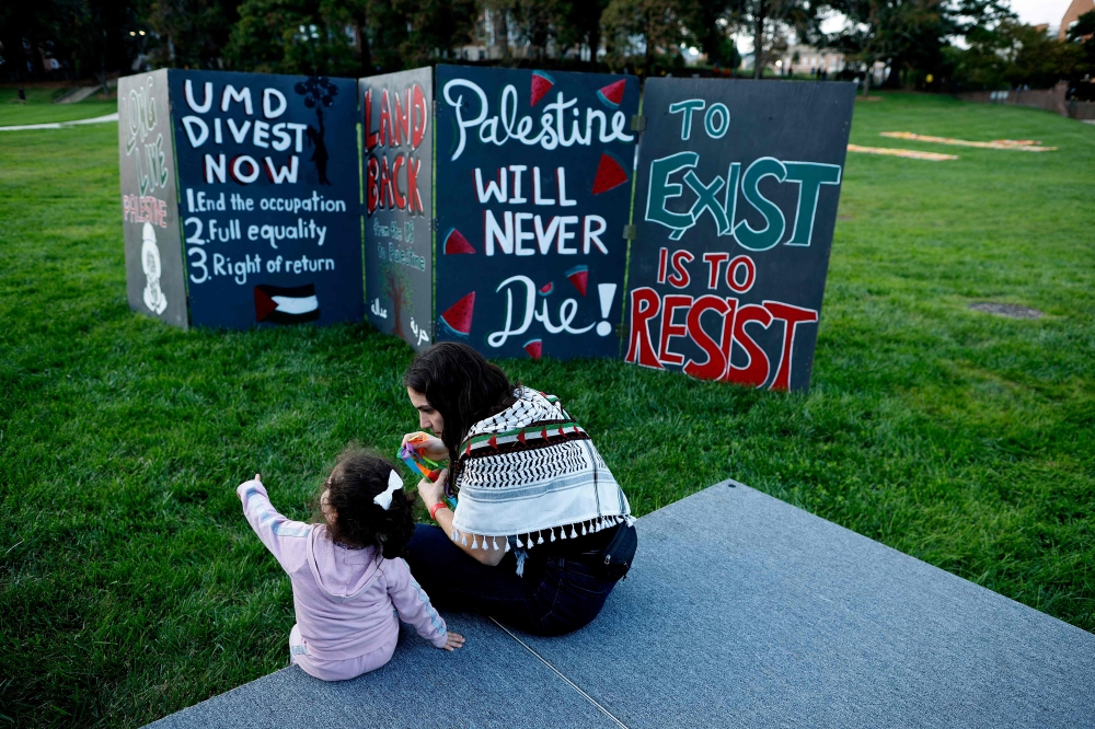 People prepare for a vigil organised by the Students for Justice in Palestine along McKeldin Mall in the heart of the University of Maryland campus on October 07, 2024 in College Park, Maryland, US. — AFP pic