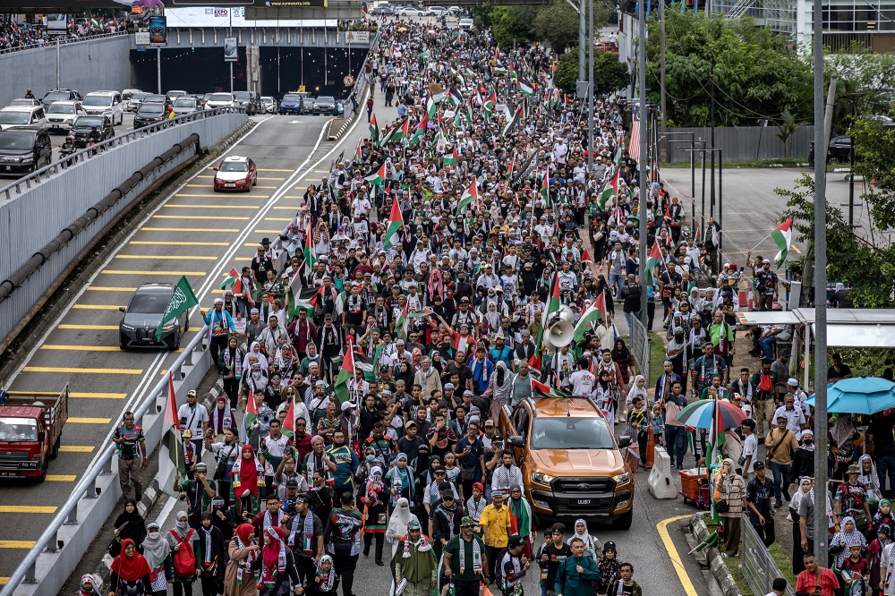 Pro-Palestinian demonstrators hold placards as they march to US Embassy during a rally to mark the first anniversary of Al-Aqsa storm in Kuala Lumpur on October 12, 2024. — Picture by Firdaus Latif