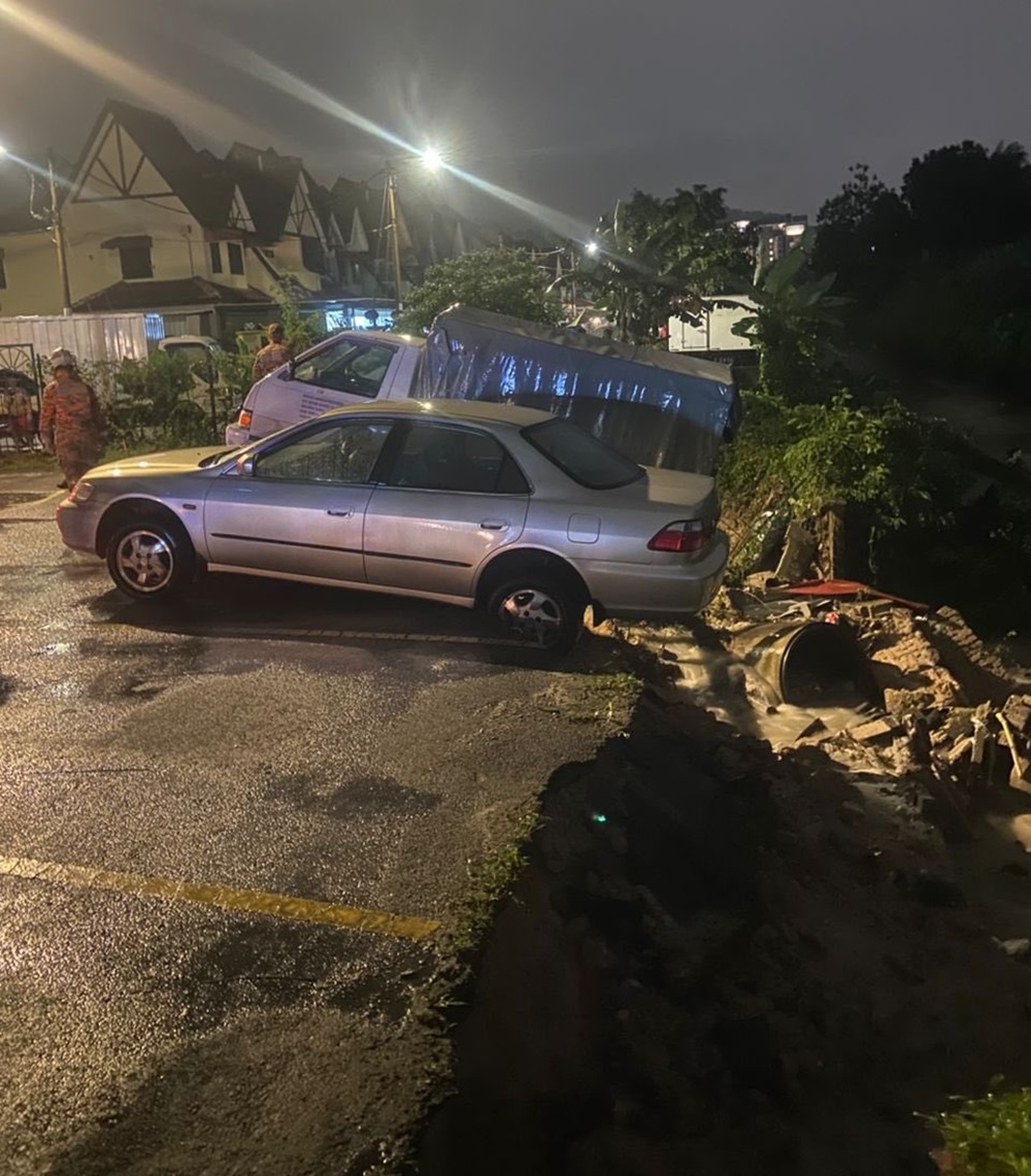 Prolonged heavy rain has caused the riverbank at Taman Lembah Maju in Ampang near here to collapse, damaging two vehicles. — Picture courtesy of Fire and Rescue Dept