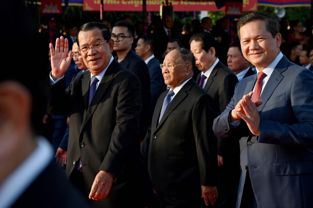 President of the Cambodian People’s Party (CPP) Hun Sen (left), Honorary President of the Cambodian People’s Party (CPP) and Cambodia’s Prime Minister Hun Manet (right) greet supporters during a ceremony marking the 45th anniversary of the fall of the Khmer Rouge regime in Phnom Penh January 7, 2024. — AFP pic