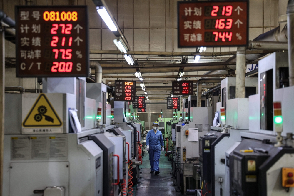 An employee works on an aluminium piston ring production line at a factory that produces car parts in Binzhou, Shandong province October 14, 2024. — AFP pic