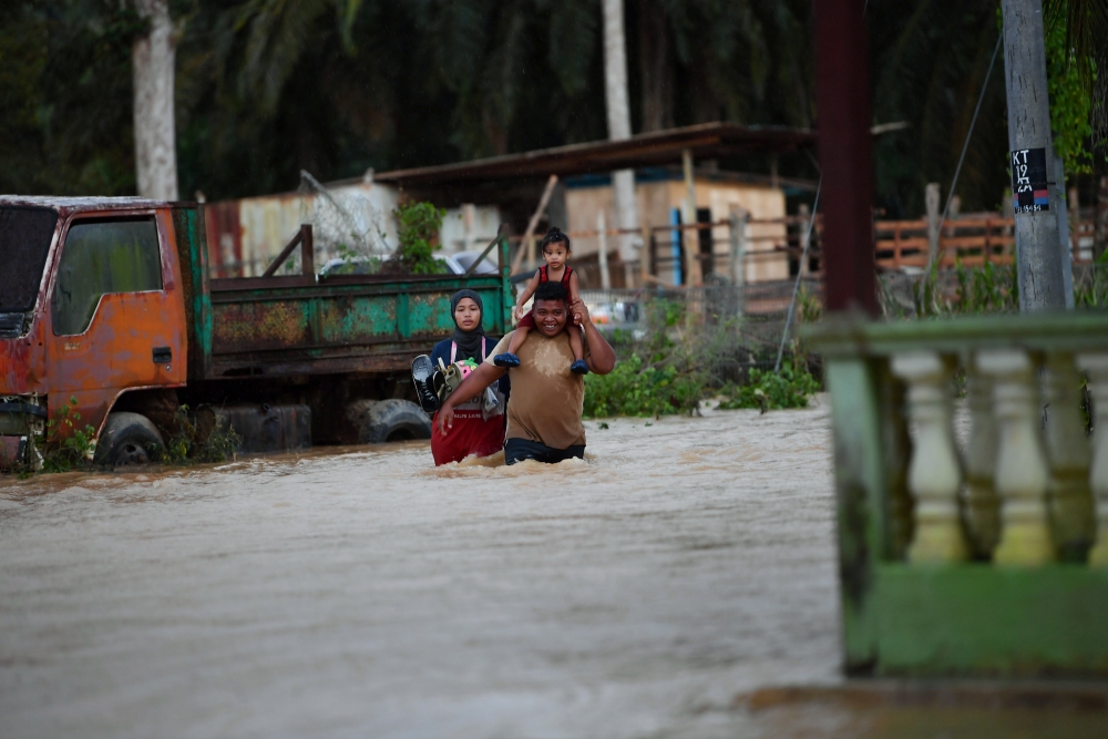 Residents wade through floodwaters in Kuala Slim in Perak October 14, 2024. — Bernama pic