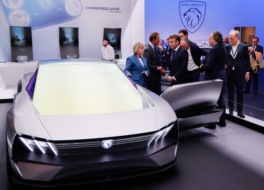 French President Emmanuel Macron examines a Peugeot Inception concept car as he visits the Stellantis stand at the Paris Motor Show at Paris Expo Porte de Versailles in Paris October 14, 2024. — Ludovic Marin/Pool/AFP pic 
