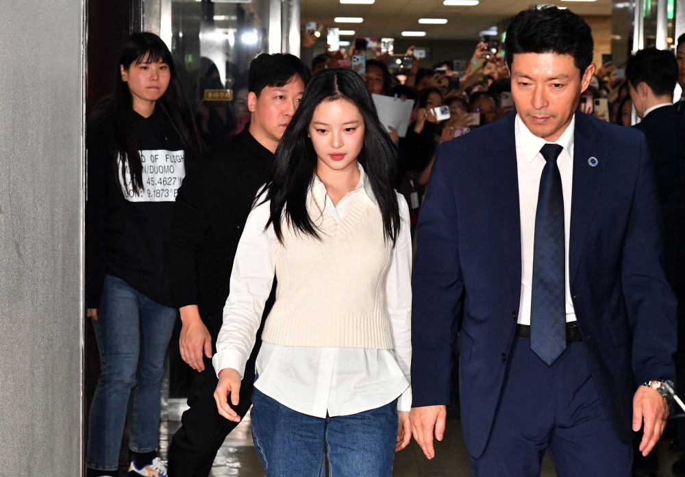 New Jeans' Hanni (centre) arrives to testify at the National Assembly in Seoul on October 15, 2024. — AFP pic