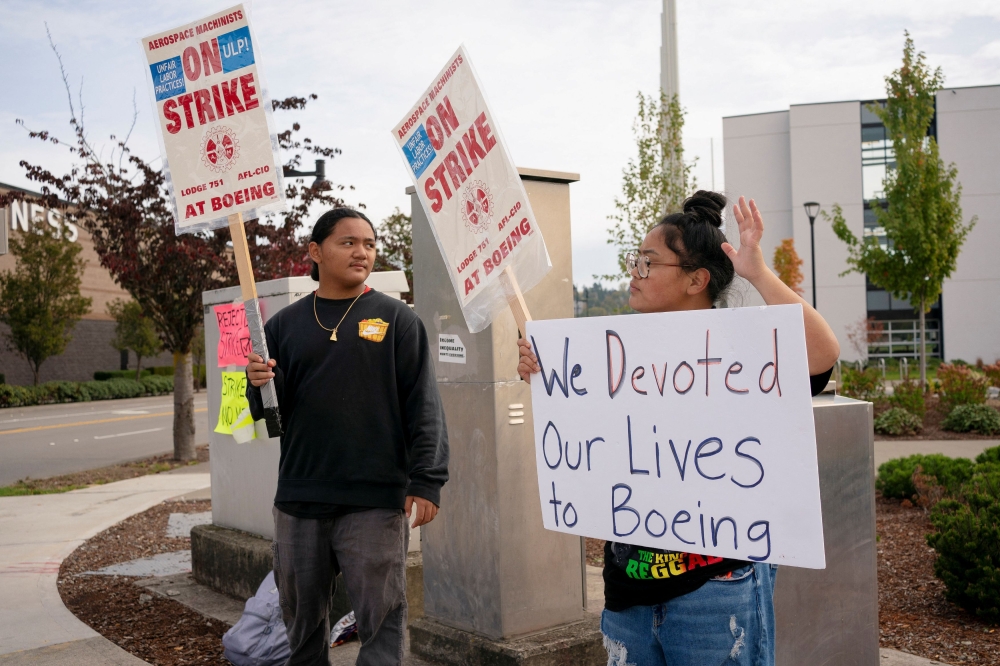 Family members of a Boeing worker hold signs at a picket line near the entrance to a Boeing production facility in Renton, Washington October 11, 2024. — Reuters pic  
