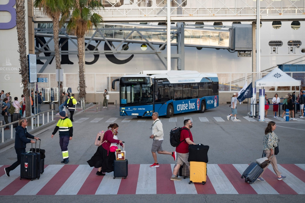 Tourists cross a street at the port in Barcelona on October  4, 2024. Tourists are flocking to Barcelona in ever increasing numbers, fueling anger among locals who complain that mass tourism in driving up housing prices and overwhelming public spaces in Spain's second city. — AFP pic