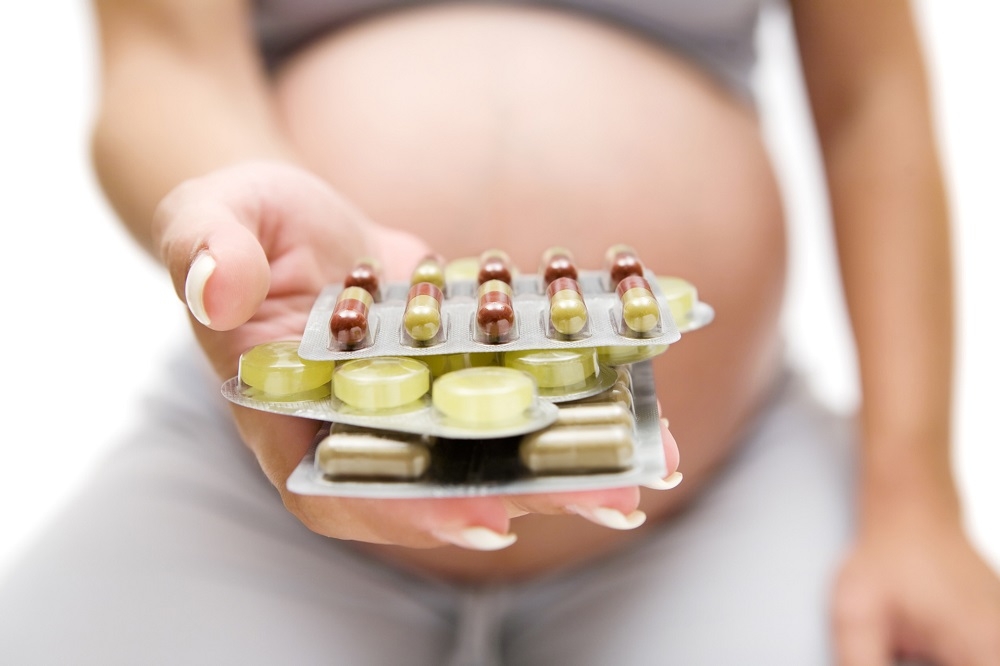 This illustrative photo shows a pregnant woman displaying strips of medication. — AFP pic