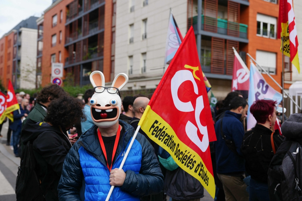 A protester wears a mask bearing the likeness of a 