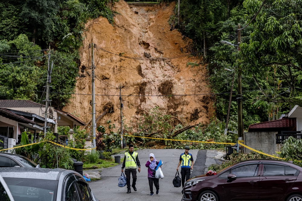 Police help residents evacuate their houses after a landslide at Taman Melawati on October 15, 2024. — Picture by Firdaus Latif