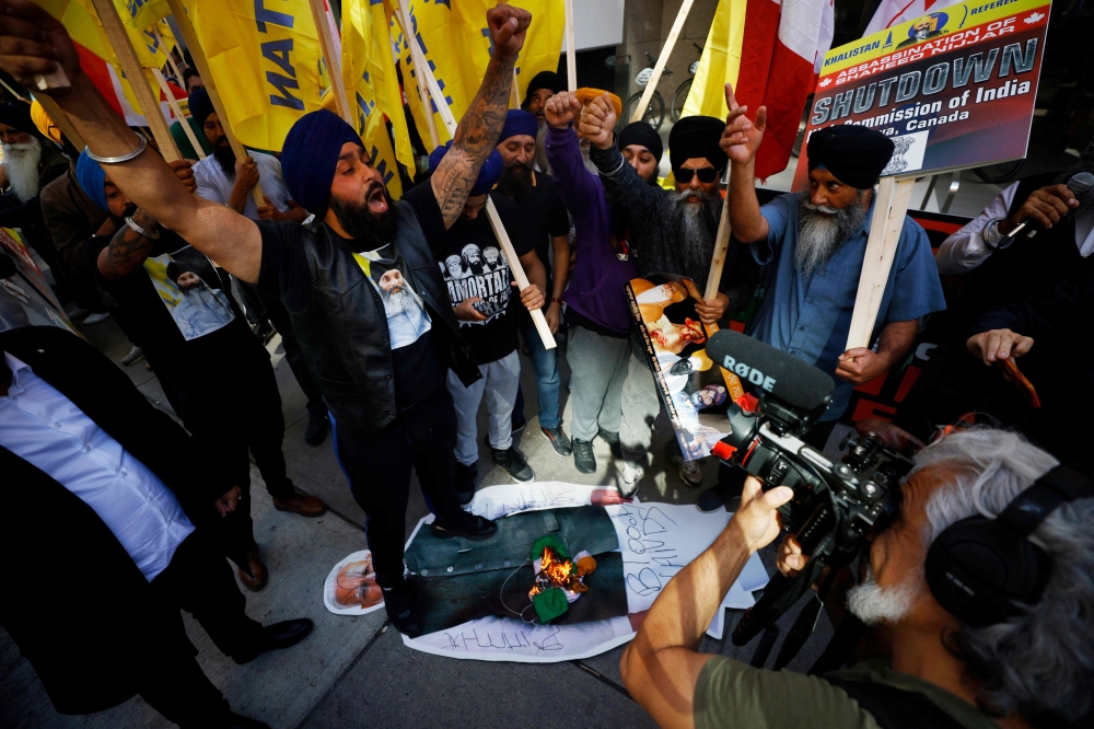Demonstrators burn an Indian flag and deface a placard depicting Indian prime minister Narendra Modi during a Sikh rally outside the Consulate General of India, in Toronto, Ontario, Canada, on September 25. — AFP pic