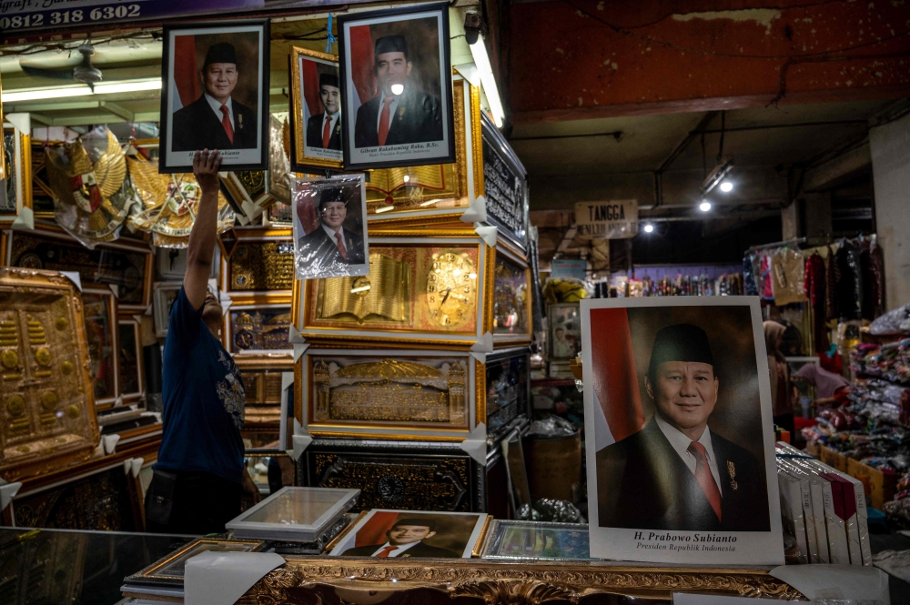 A vendor arranges pictures of Indonesia's president-elect Prabowo Subianto (left) and vice president-elect Gibran Rakabuming Raka (right) at a stall in Surabaya on October 17, 2024. — AFP pic