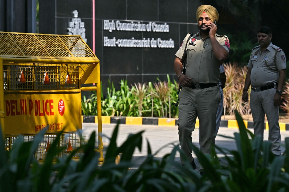 Indian policemen stand guard outside the entrance of the Canadian High Commission, in New Delhi on October 15, 2024. — AFP pic