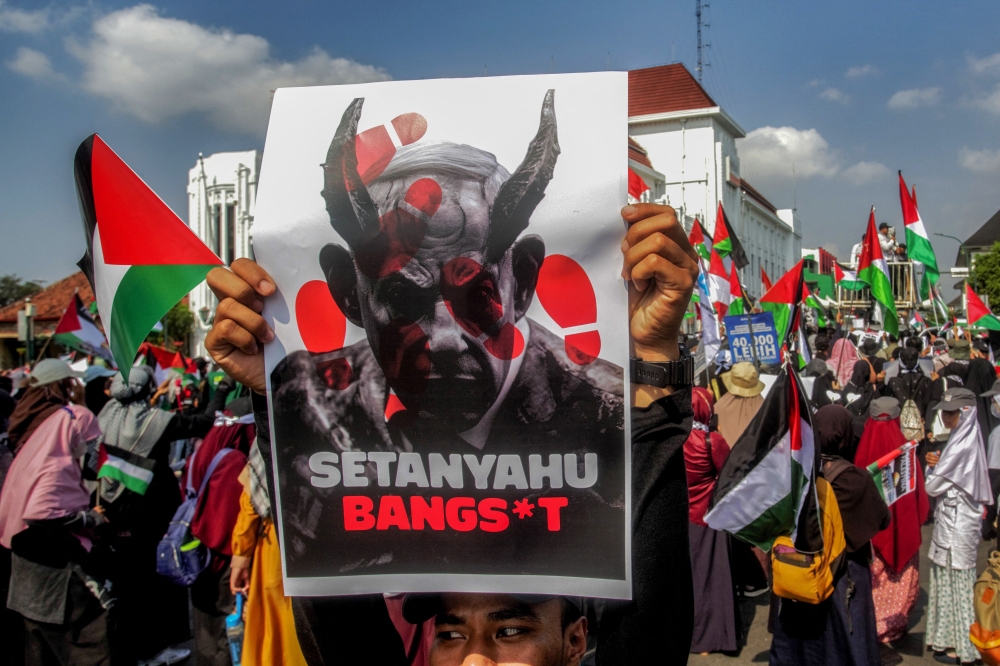 A pro-Palestinian demonstrator holds a placard depicting Israeli Prime Minister Benjamin Netanyahu as a devil that reads