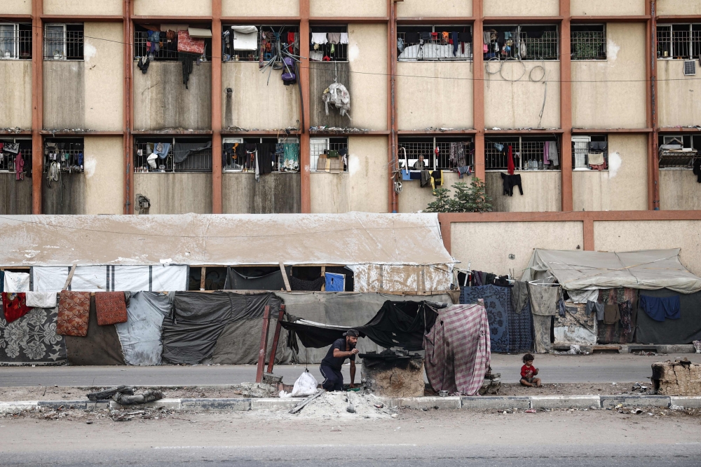 A Palestinian man bakes bread at a make-shift camp for the internally displaced in Deir al-Balah in the central Gaza Strip on October 17, 2024. — AFP pic