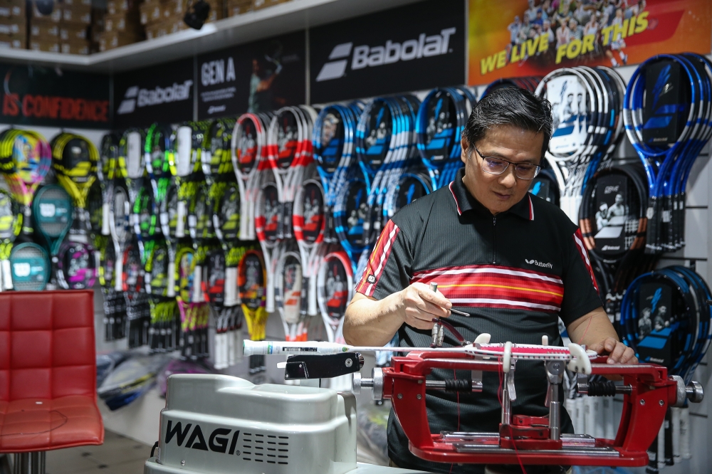 Ting Wah Fun strings a badminton racquet in his store at Pertama Complex in Kuala Lumpur on October 15, 2024. — Picture by Yusof Mat Isa