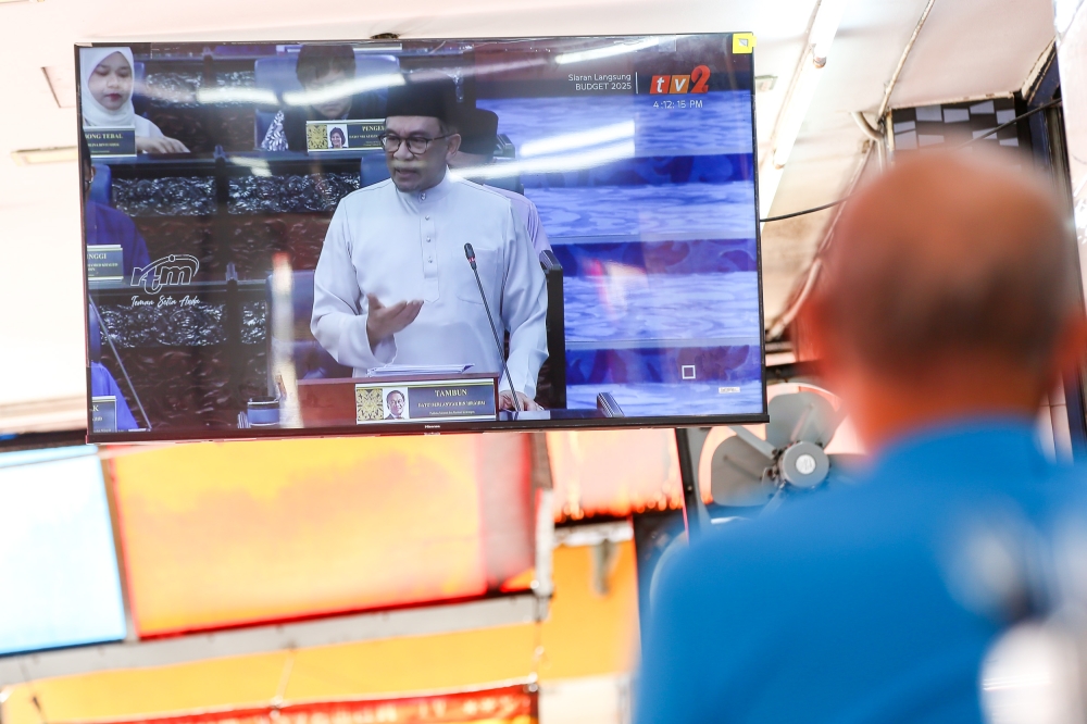 Live telecast of Prime Minister Datuk Seri Anwar Ibrahim tabling Budget 2025 in a eatery in Puchong yesterday. — Pic by Choo Choy May 