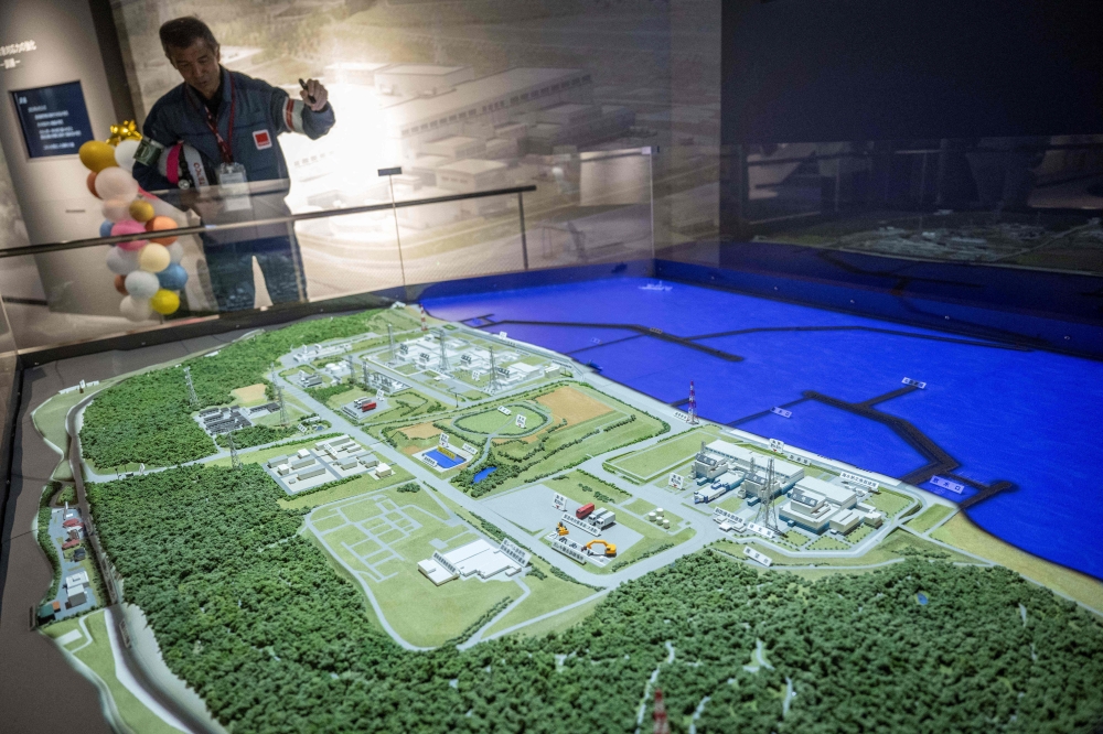 Masaki Daito, deputy superintendent of the Kashiwazaki-Kariwa nuclear power station, shows a diorama of the world’s biggest nuclear power plan in Japan’s Niigata prefecture that has a new tsunami wall to prevent a recurrence of the catastrophe that befell the Fukushima nuclear station in 2011. — AFP pic