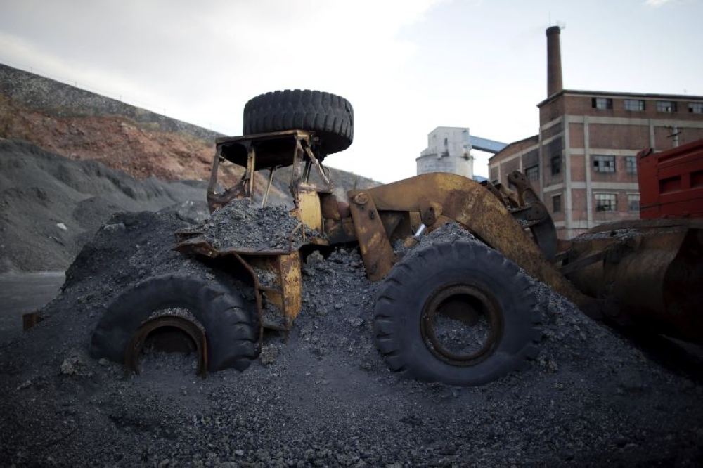 An abandoned excavator is partially covered by coal waste at a coal mine of the state-owned Longmay Group on the outskirts of Jixi, in Heilongjiang province, China, November 5, 2015. — Reuters pic