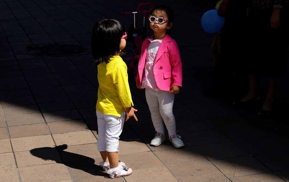 A file photograph shows children waiting with their families next to a bus stop in central Pyongyang, on September 10, 2018. — Reuters pic