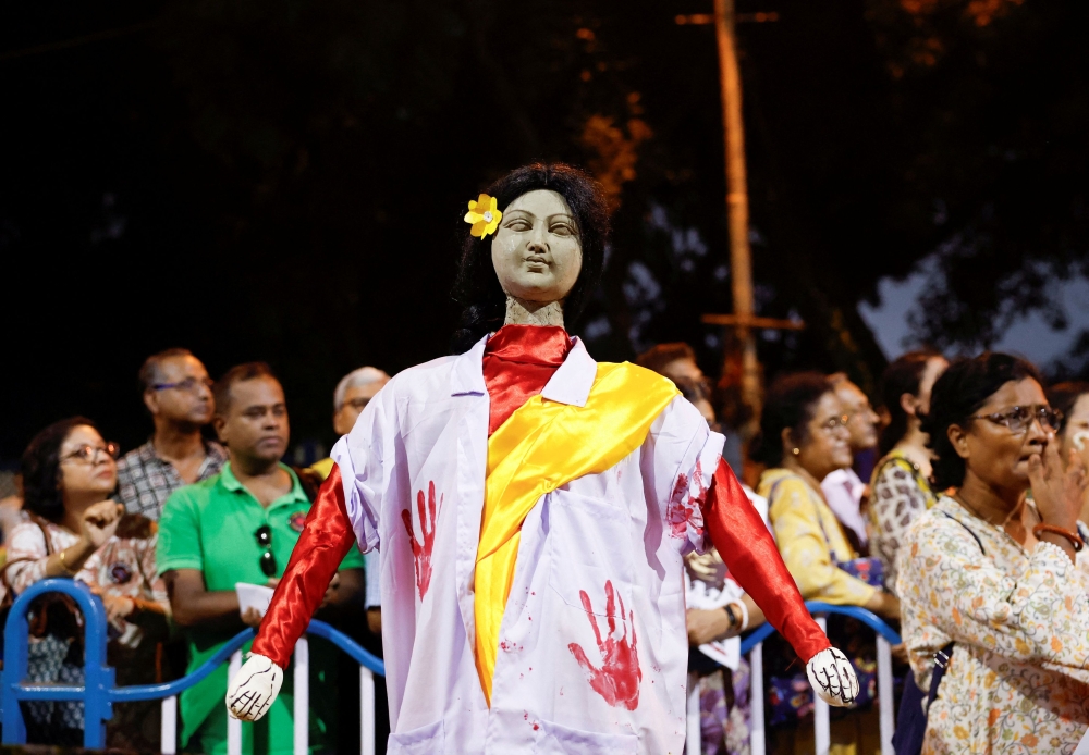 People stand behind an idol wearing a doctor's coat as they attend a protest condemning the rape and murder of a trainee medic at a government-run hospital, in Kolkata, India, October 15, 2024. — Reuters pic