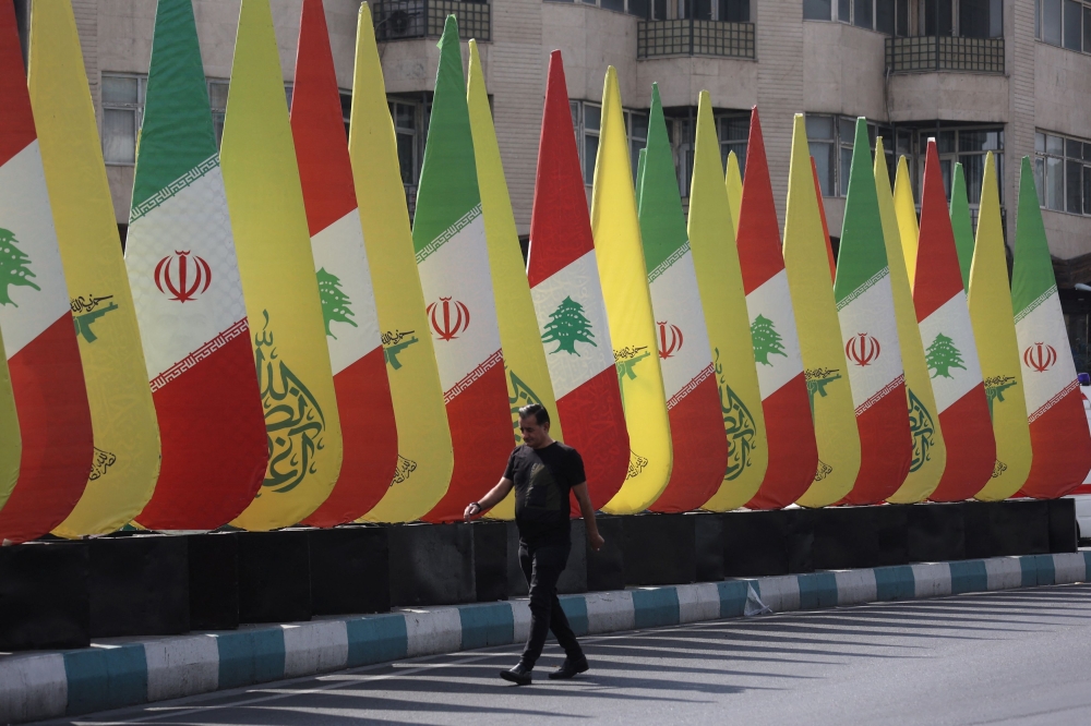 An Iranian man walks next to an installation with the flags of Iran, Hezbollah and Lebanon in a street in Tehran, Iran, October 18, 2024. — Wana pic via Reuters