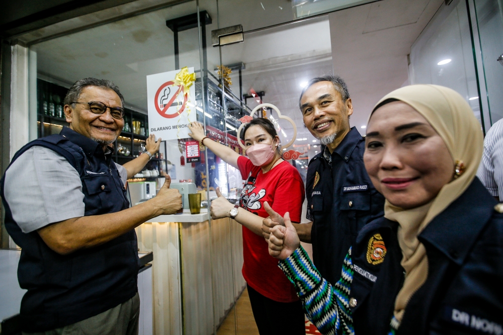 Health Minister, Datuk Seri Dr Dzulkefly Ahmad (left) sticking a 