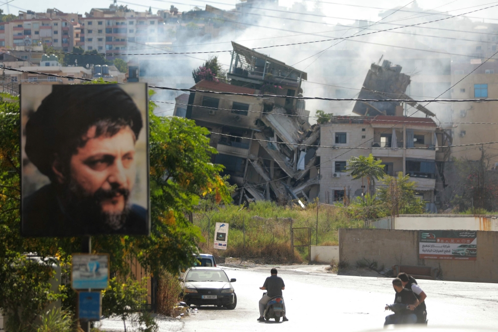People drive next to a building, targeted in an Israeli airstrike the night before, in Beirut's southern suburbs on October 20, 2024, amid the ongoing war between Hezbollah and Israel. — AFP pic