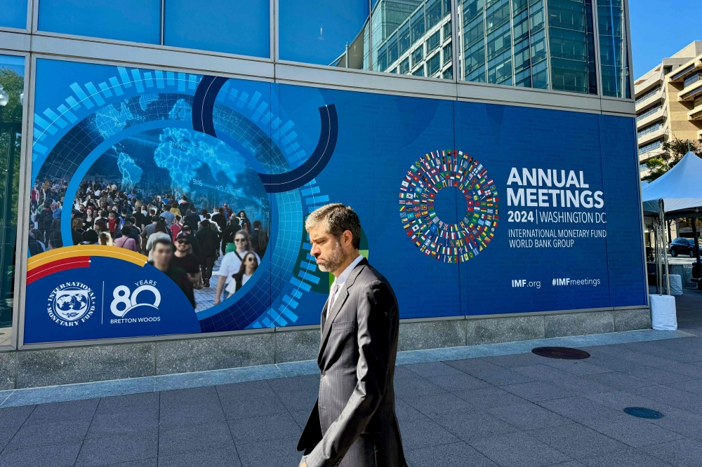 A man walks past signage for the the 2024 IMF/World Bank Annual Meetings outside of the headquarters of the International Monetary Fund in Washington, DC on October 18, 2024. — AFP pic 
