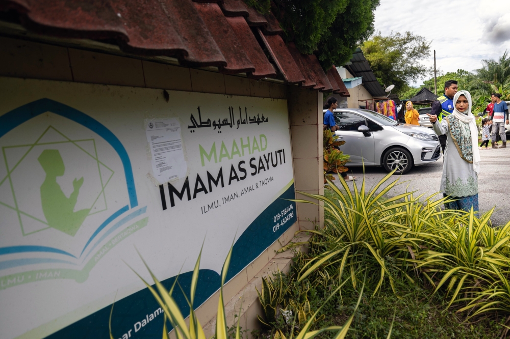 The daughter of former leader Al-Arqam Ashaari Muhammad, Ummu Atiyah, points to a signboard showing the location where she claimed to have been locked up for about a month at the GISB Holdings Sdn Bhd (GISBH) settlement in Batu Hampar, Perak October 20, 2024. — Bernama pic