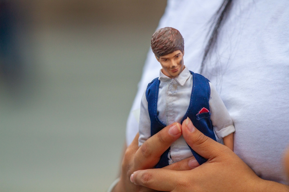 A fan of late British singer Liam Payne carries an action figure of Payne. — AFP