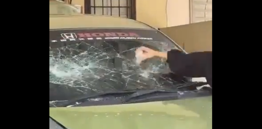 A screen capture shows a woman smashing the windscreen of a vehicle being repossessed. 