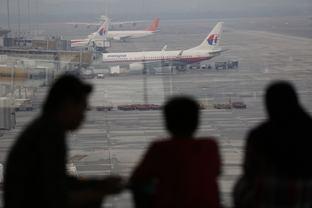 File photo of people looking at planes through the window of the KLIA departure hall viewing area in Sepang. — Picture by Saw Siow Feng
