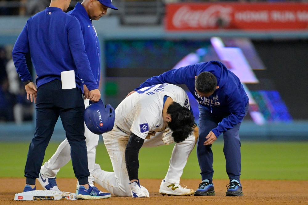 Los Angeles Dodgers manager Dave Roberts and staff attend to Shohei Ohtani at second base after an apparent injury in the seventh inning against the New York Yankees during game two of the 2024 MLB World Series in Los Angeles October 26, 2024. — Jayne Kamin-Oncea-Imagn Images pic via Reuters