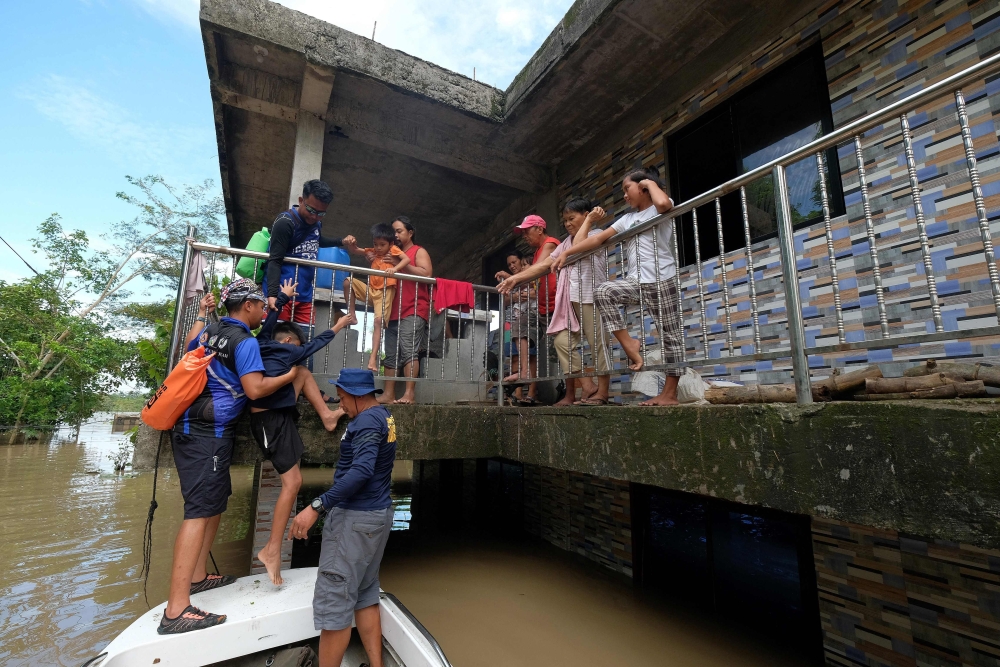 Rescuers evacuate a family from their submerged house brought about from Tropical Storm Trami in Bula town, Camarines Sur province, South of Manila on October 26, 2024. — AFP pic