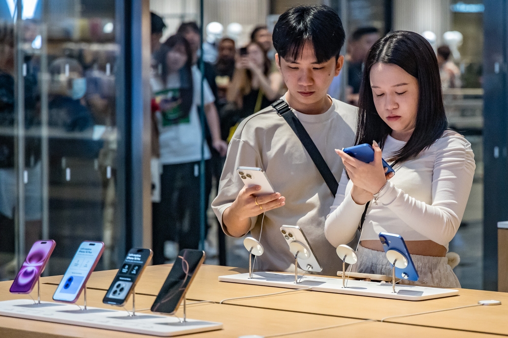Customers try out the newly launched iPhone 16 at an Apple store at the Tun Razak Exchange (TRX) in Kuala Lumpur September 20, 2024. — Picture by Firdaus Latif