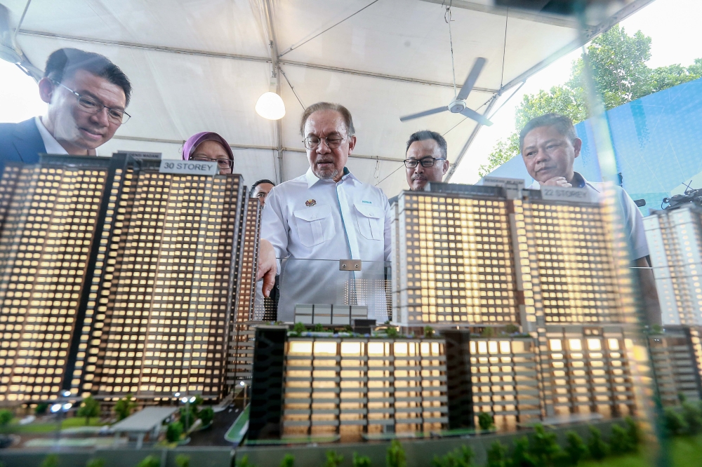 Anwar (centre) takes a closer look at a model of the “Residensi Madani Putrajaya” low cost housing project during its launch in Putrajaya on October 28, 2024. — Picture by Sauti Zainudin