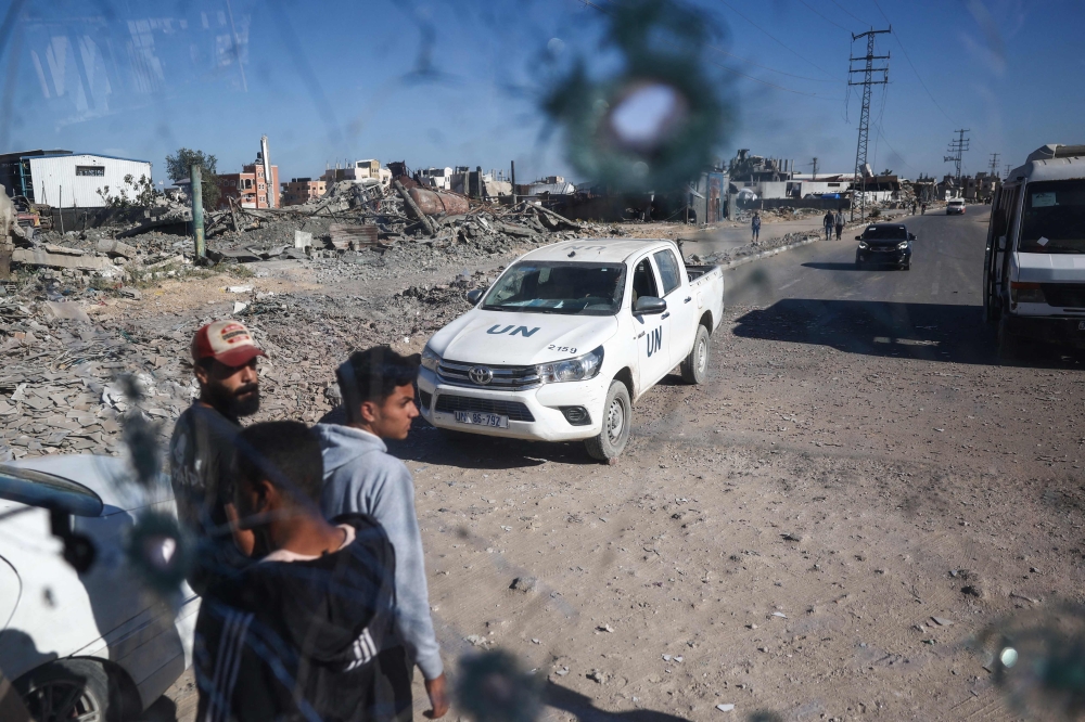 People and a UN Relief and Works Agency for Palestine Refugees (UNRWA) vehicle are seen through the shrapnel-riddled windscreen of a bus that was damaged when an Israeli artillery shell reportedly landed near it on Gaza's main Salah al-Din road, outside Deir el-Balah in the central Gaza Strip, on October 24, 2024, amid the ongoing war between Israel and Hamas. — AFP pic