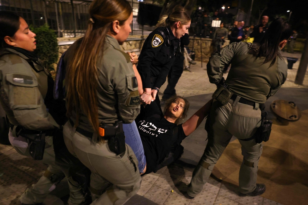 Members of Israel's police remove anti-government protesters and supporters of Israelis held hostage in Gaza since the October 2023 attacks by Palestinian militants, who were holding a sit-in calling for their release near the prime minister's residence in Jerusalem on October 28, 2024. — AFP pic