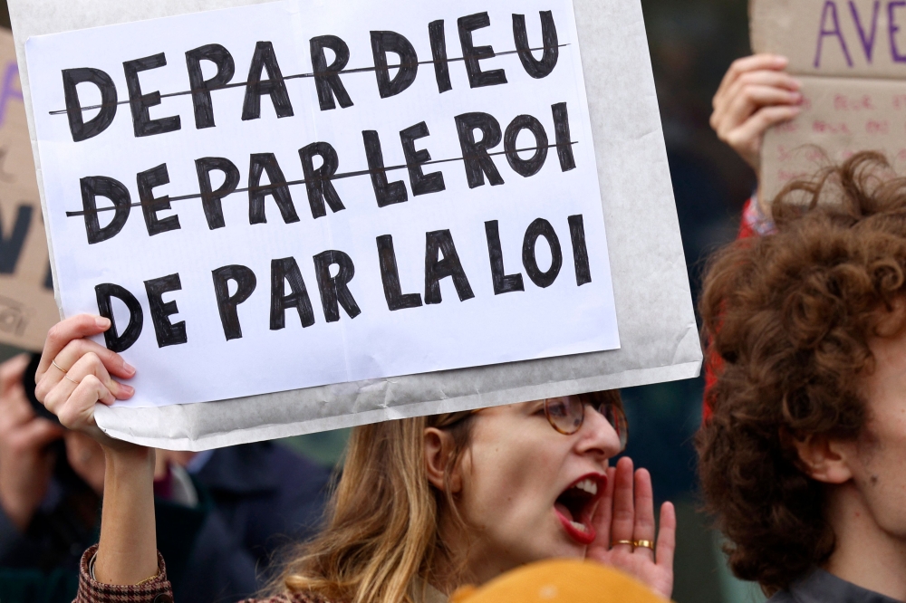 A protester hold a slogan which reads ‘Depardieu (by the god), by the king, by the law’ during a demonstration of various organisations outside the Paris courthouse where French actor Gerard Depardieu to be tried on sexual assault charges, in Paris October 28, 2024. Depardieu, 75-years-old, asked for a delay to the start of his trial on sexual assault charges, saying his health prevented him from attending the proceedings, with numerous other complaints and a possible second court case already lying in wait on October 28, 2024. — AFP pic
