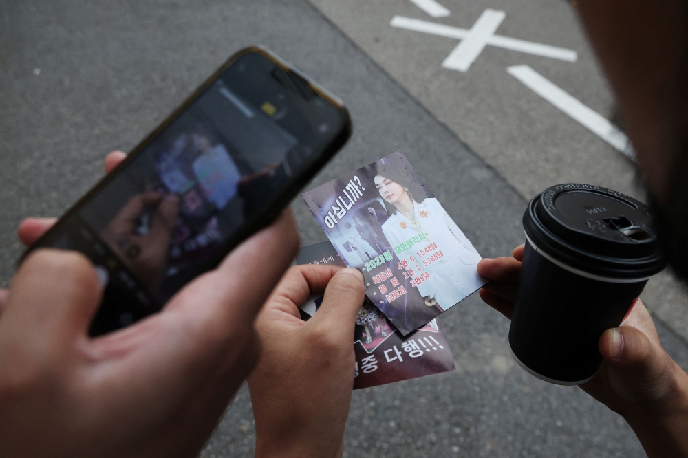 People look at a North Korean propaganda leaflet denouncing South Korean President Yoon Suk Yeol and his wife Kim Keon Hee, apparently carried by balloons sent from North Korea, near the Presidential Office in Seoul, South Korea, October 24, 2024. — Reuters